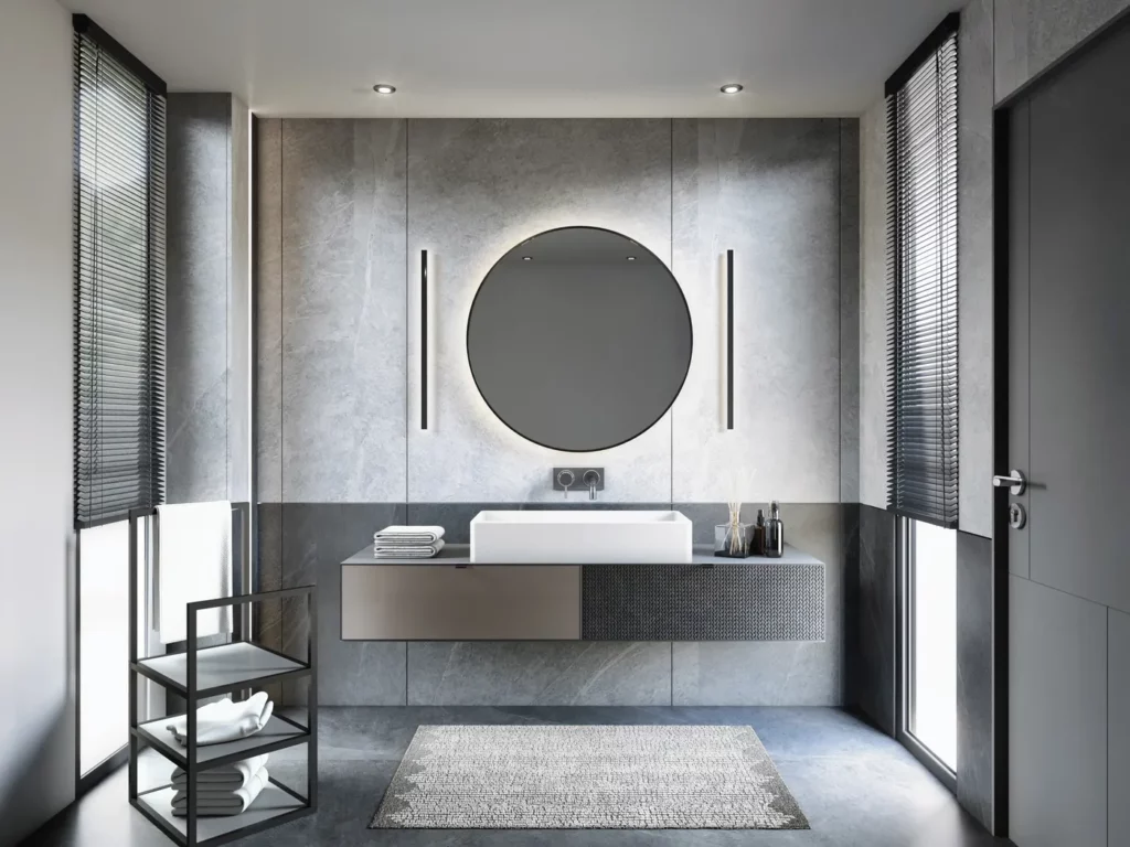 Salle de bain minimaliste grise : Vasque blanche rectangulaire sur un meuble gris anthracite avec un grand miroir rond et des stores vénitiens.