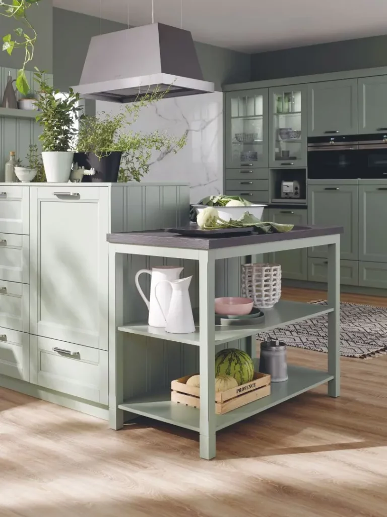 Cuisine rustique vert sauge : Aménagement de cuisine aux façades vert d'eau avec îlot central ouvert et étagères de rangement en bois.