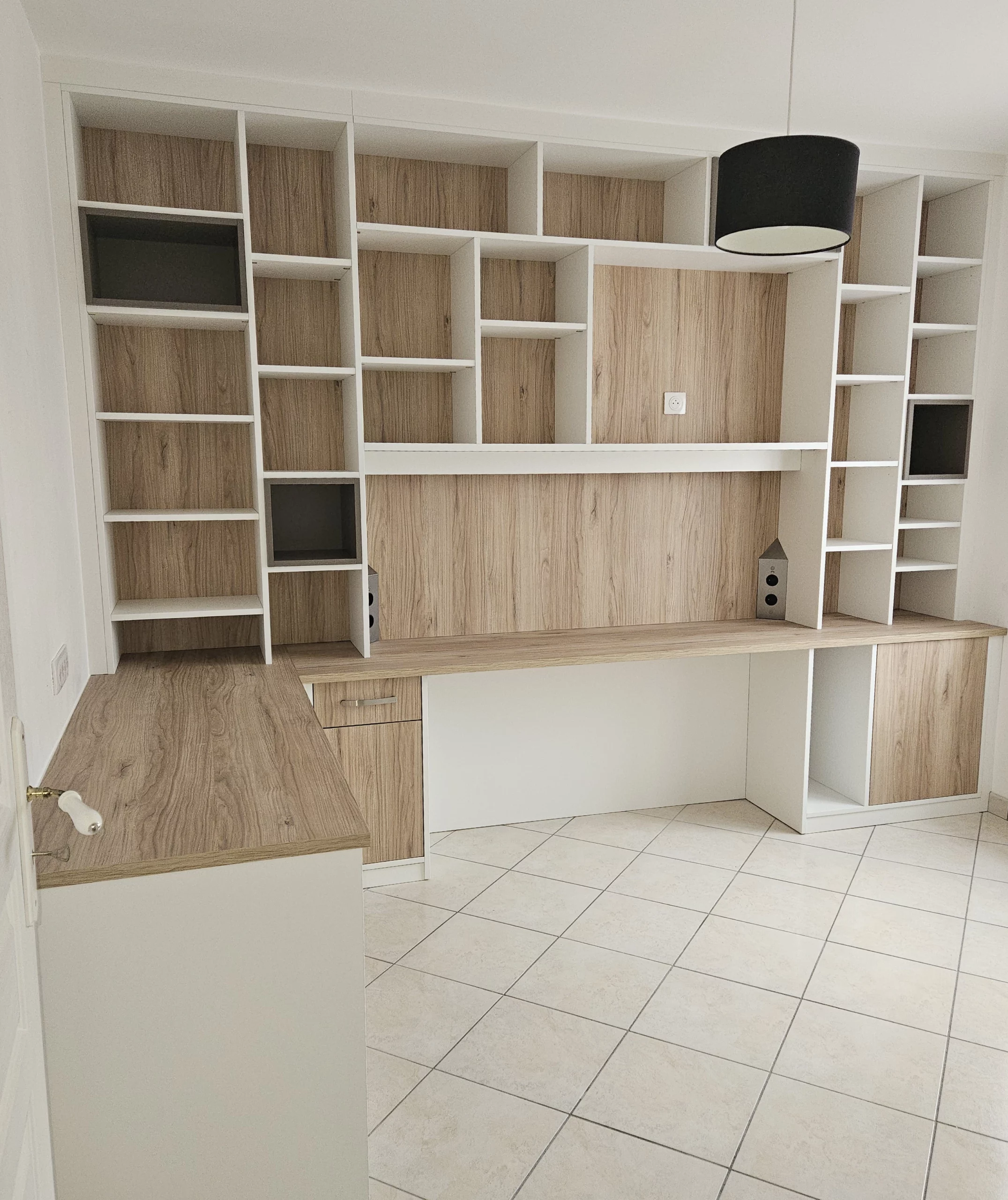Aménagement de bureau à domicile fonctionnel avec de nombreuses niches de rangement, des placards fermés et un éclairage intégré sous les étagères.