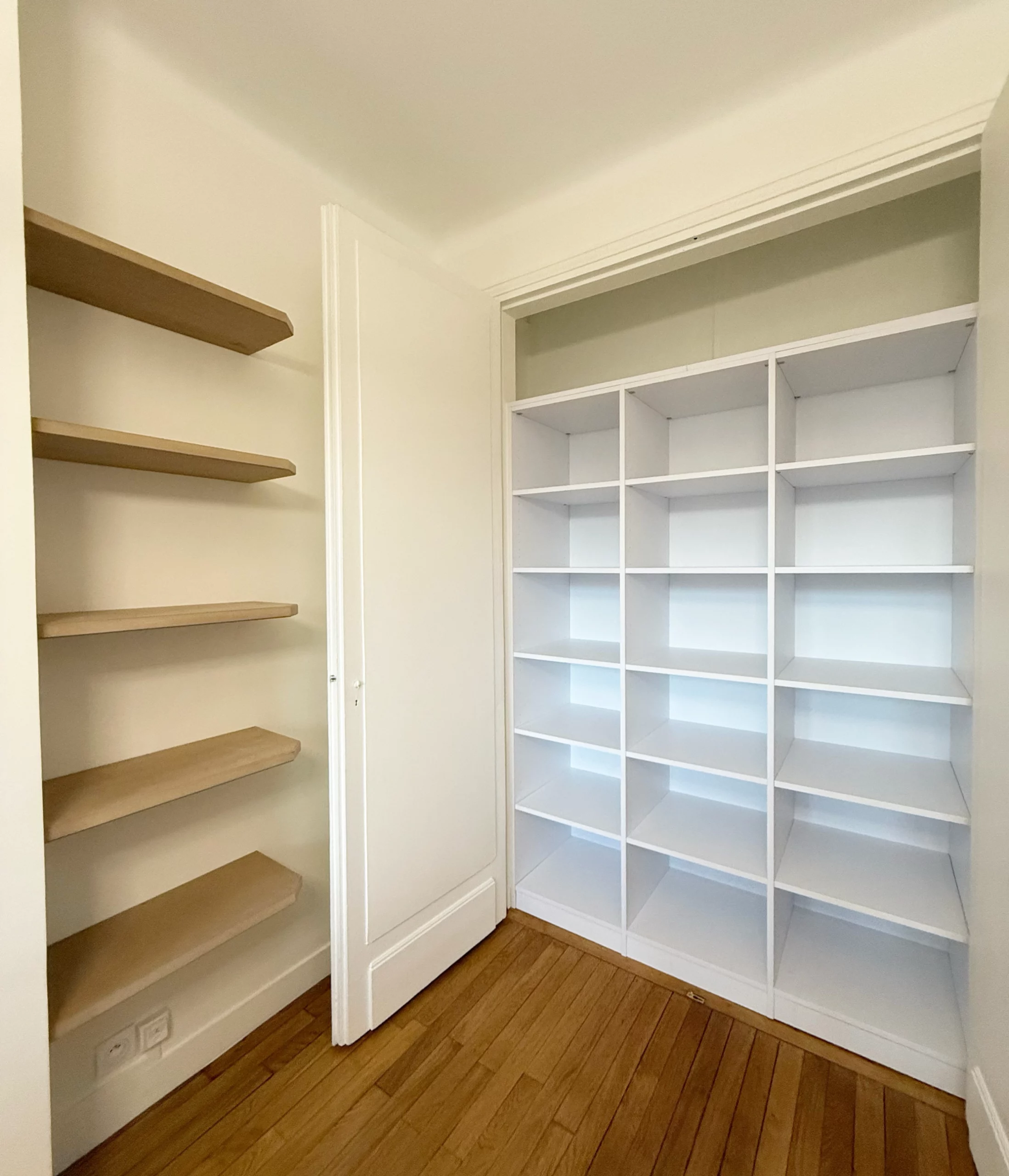 Vue d'un placard de rangement blanc sur mesure ouvert, montrant une organisation optimisée avec de nombreuses étagères pour le linge ou les accessoires.