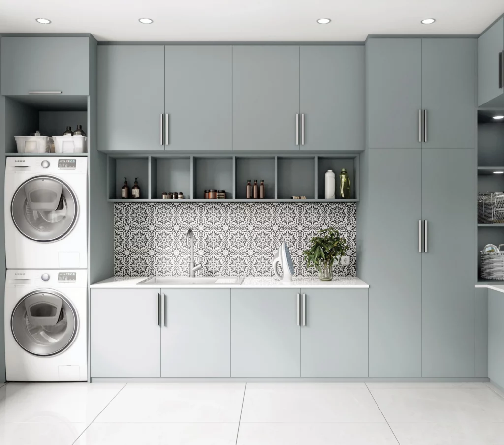 Buanderie complète bleu pastel : Grand meuble de rangement mural intégrant une machine à laver et un sèche-linge en colonne avec plan de travail.