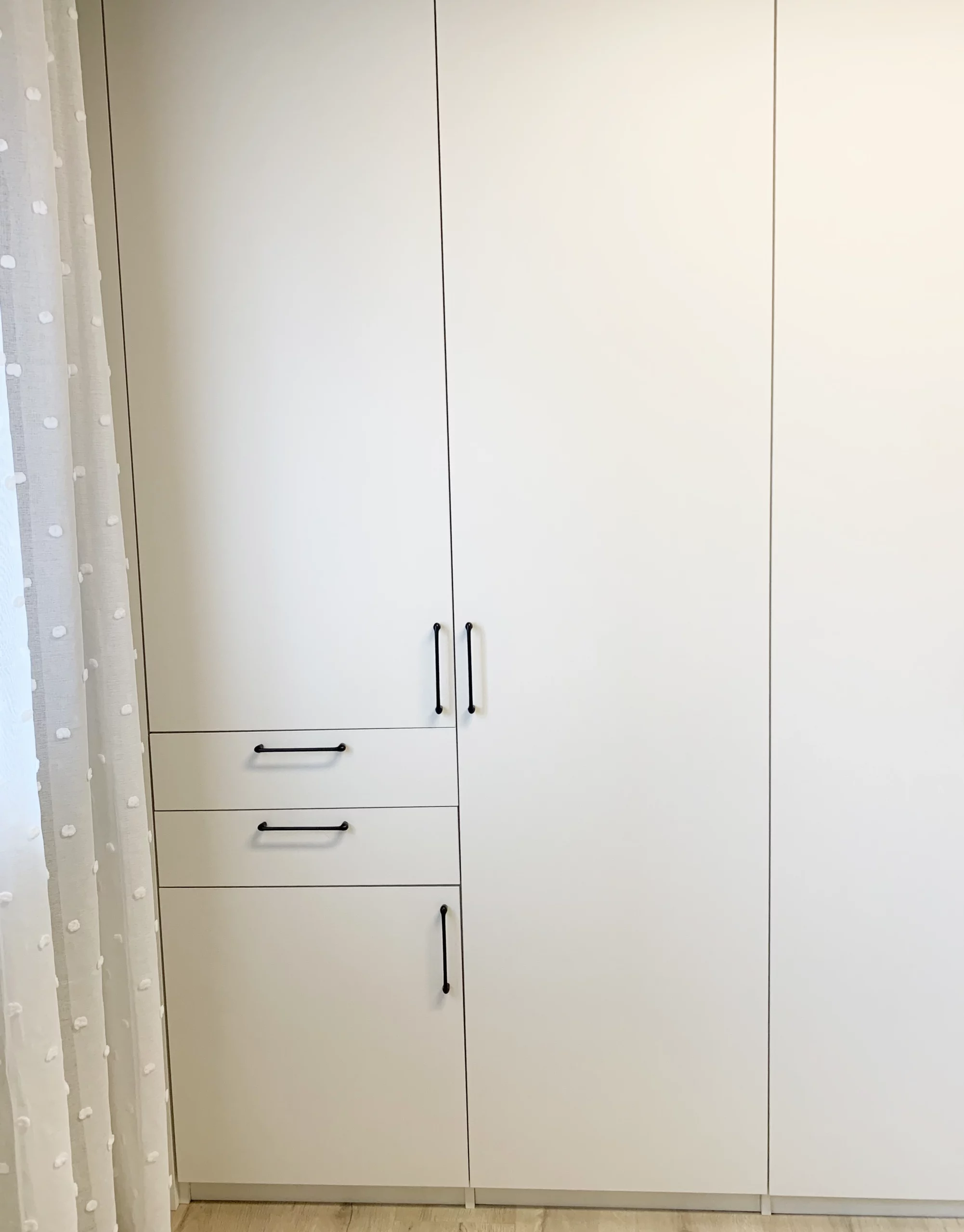 Armoire de rangement blanche encastrée comprenant une partie penderie et une colonne avec deux tiroirs extérieurs pour optimiser l'organisation.