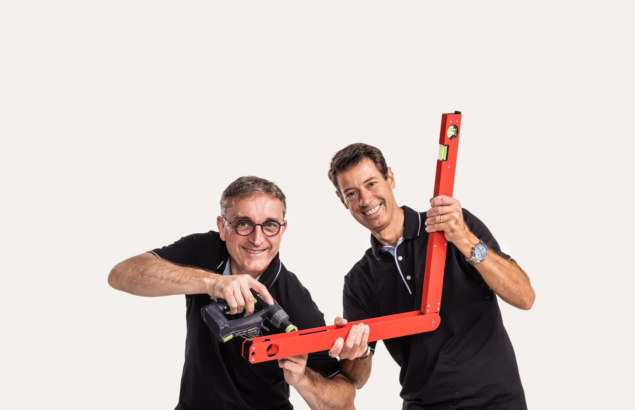 Experts poseurs en action : Deux concepteurs Venidom souriants utilisant un niveau laser rouge et une perceuse, symbolisant la précision de l'installation.