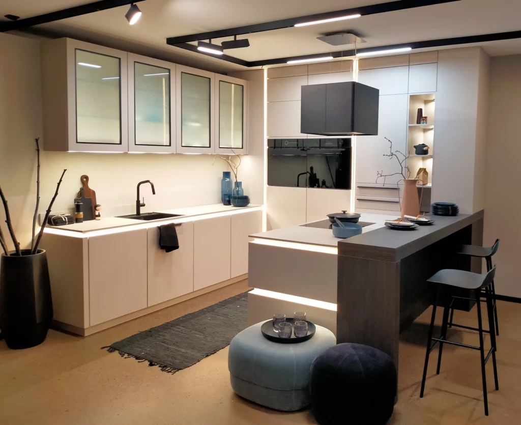 Mur d'armoires de cuisine en chêne avec double four encastré et niches de rangement ouvertes rétroéclairées.