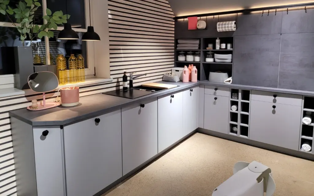 Buanderie d'angle sous pente avec façades gris clair, niches de rangement et mur à tasseaux de bois.