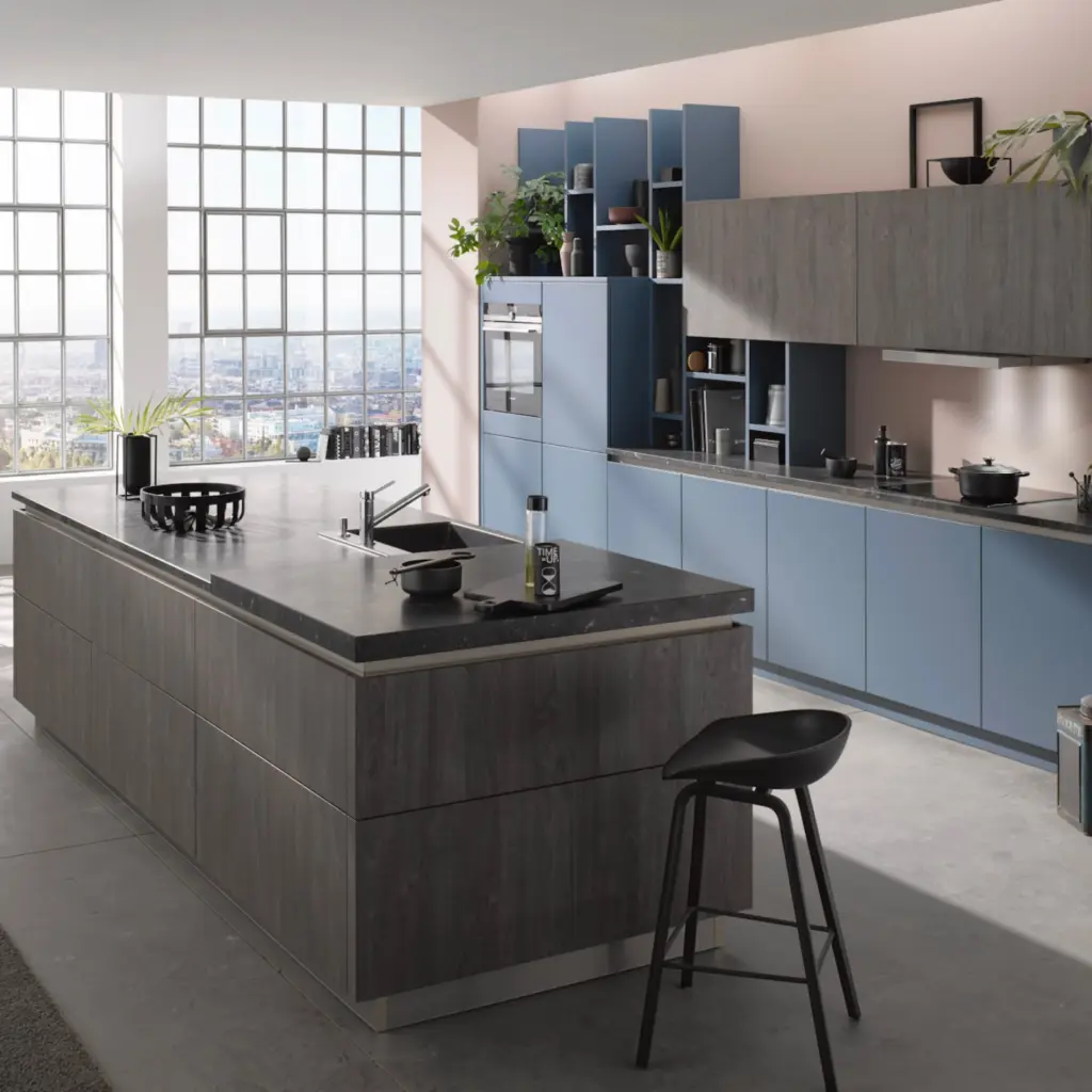 Grande cuisine design avec immense îlot central en bois sombre, meubles bleu horizon et verrière industrielle.