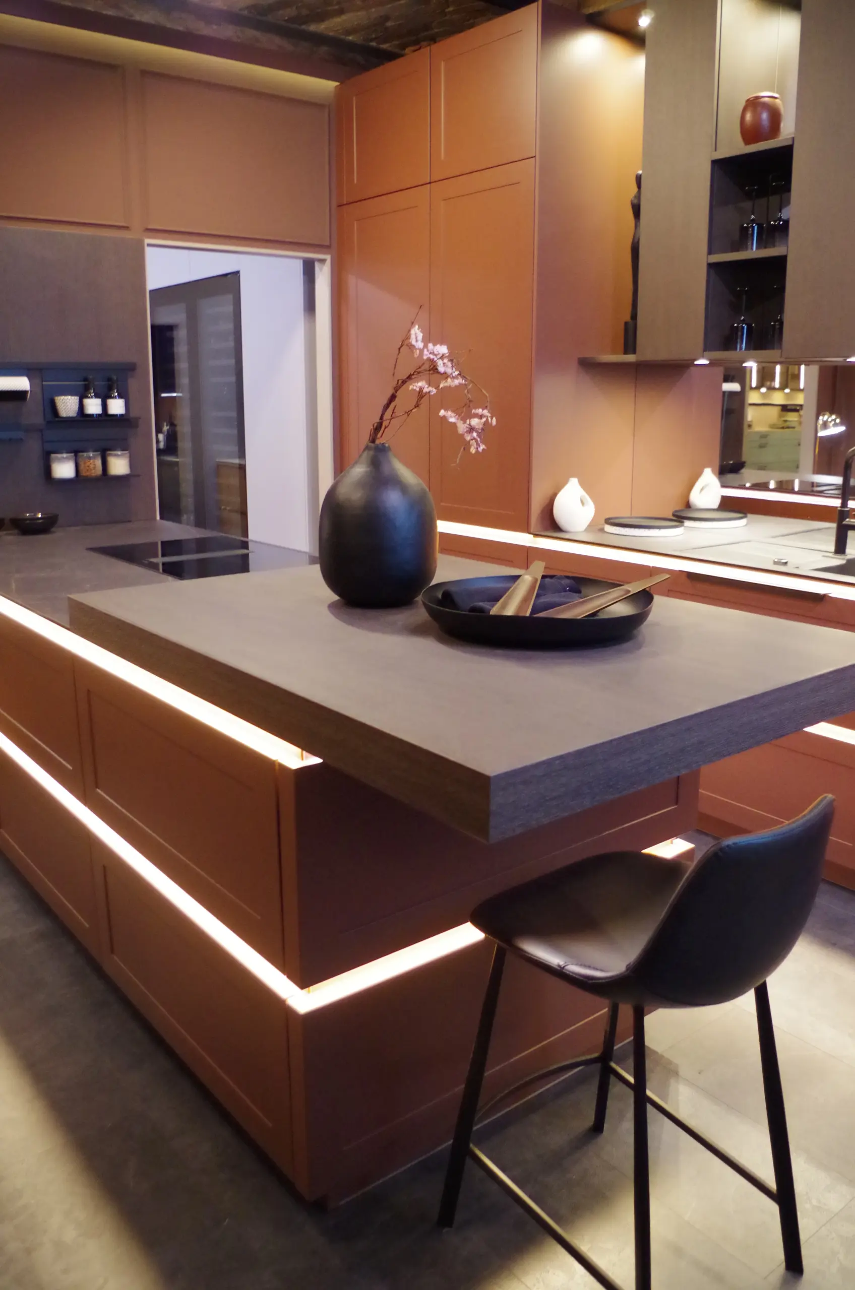 Îlot central rétroéclairé : Îlot de cuisine moderne avec éclairage LED intégré sous le plan de travail et tabouret de bar noir.