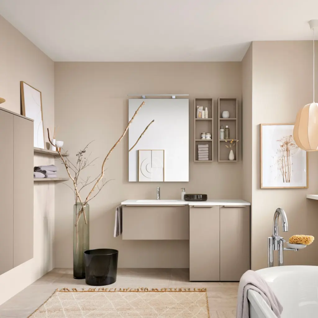 Salle de bain moderne beige sable avec meuble vasque suspendu, grand miroir et décoration épurée.