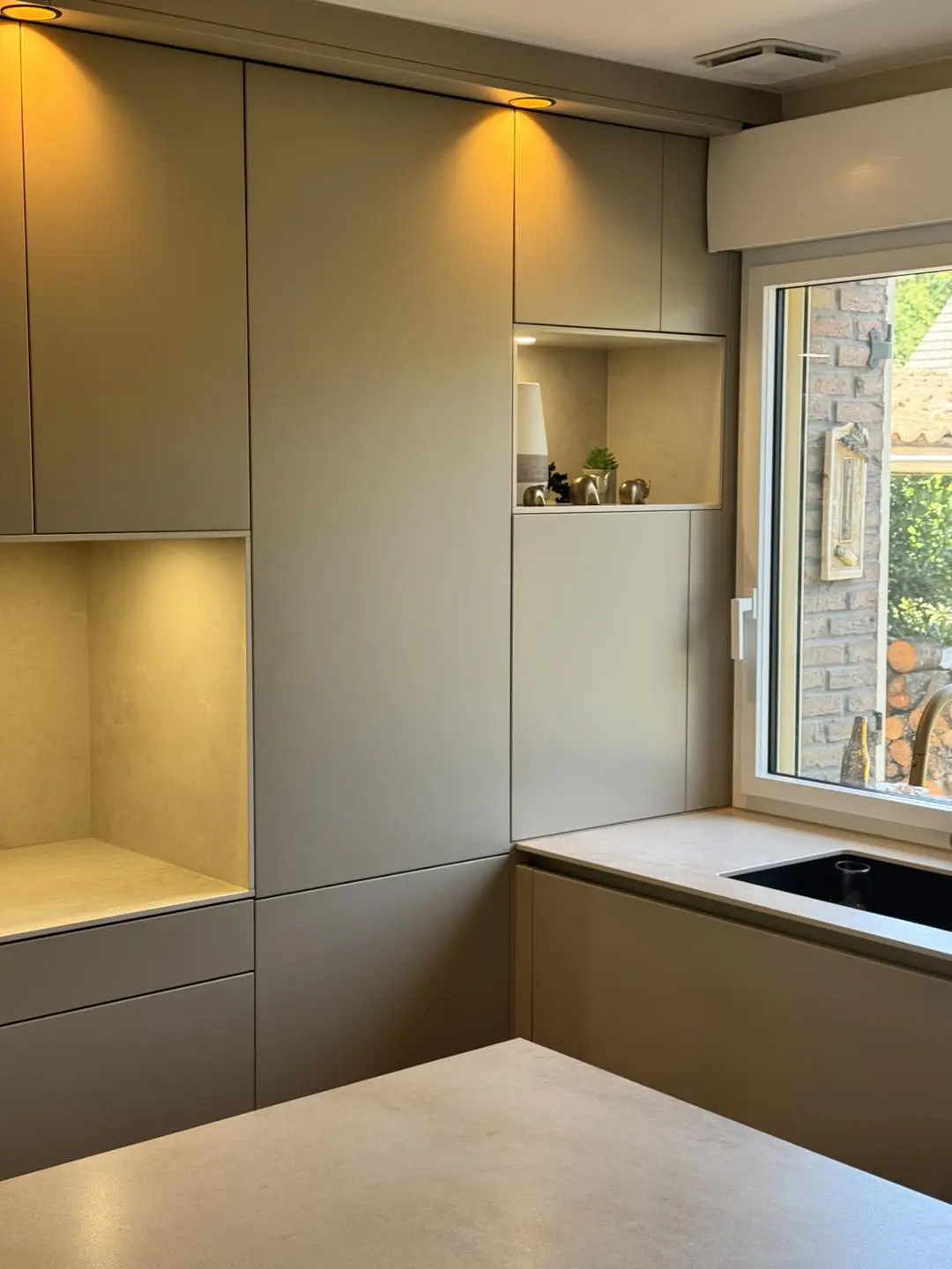 Détail d'un coin café pratique niché dans les rangements de la cuisine, avec étagère décorative et éclairage LED intégré pour libérer le plan de travail.