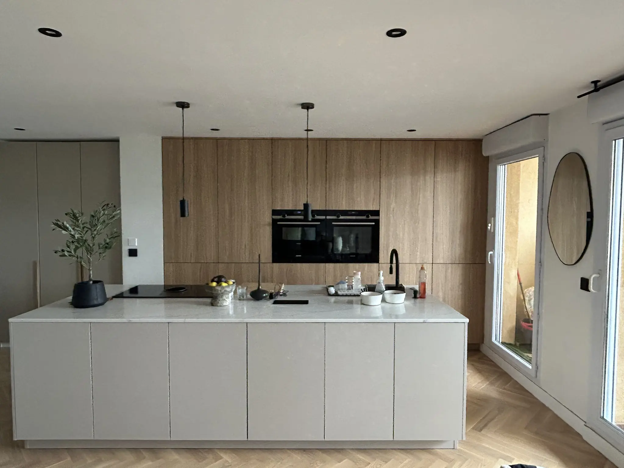 Remplacement des façades d'une cuisine avec îlot central par des teintes sable et bois miel pour créer une ambiance chaleureuse, réalisé par Laurent Magon de Venidom Antibes.