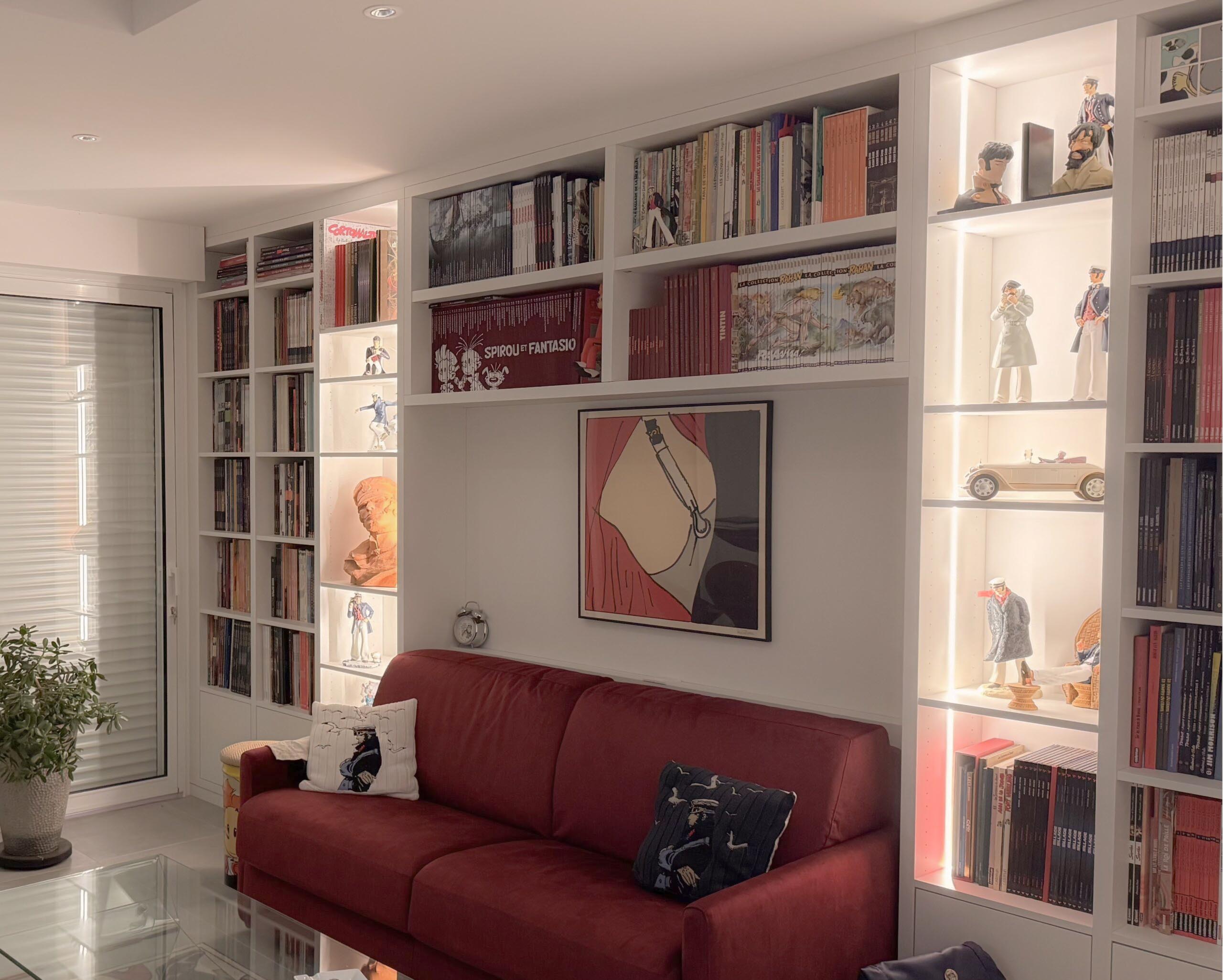 Aménagement de salon avec bibliothèque sur mesure intégrée, créant un espace cocooning dédié à la lecture avec rangements optimisés et éclairage intégré