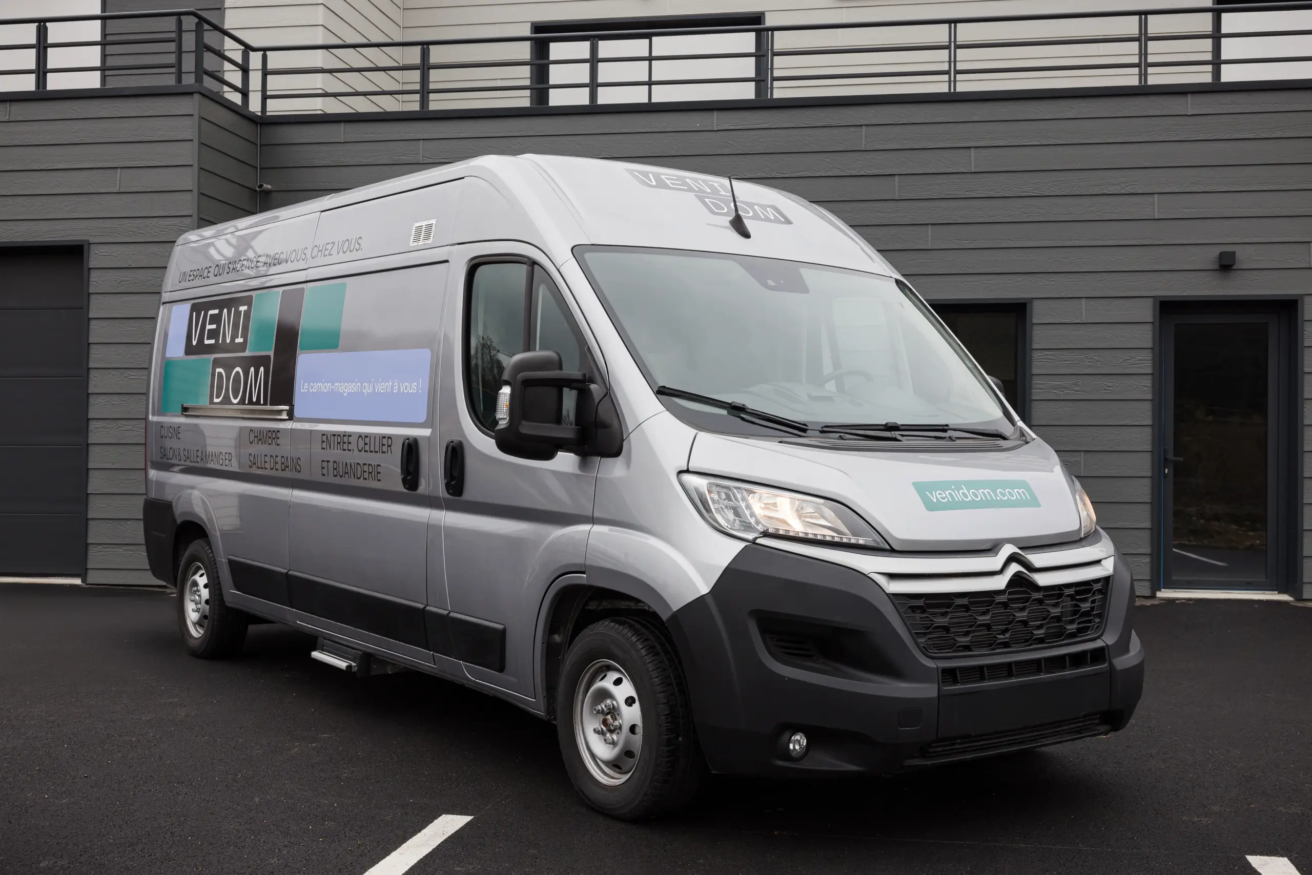 Camion magasin Venidom stationné devant une maison moderne, showroom mobile dédié à la conception d’aménagements intérieurs sur mesure à domicile.