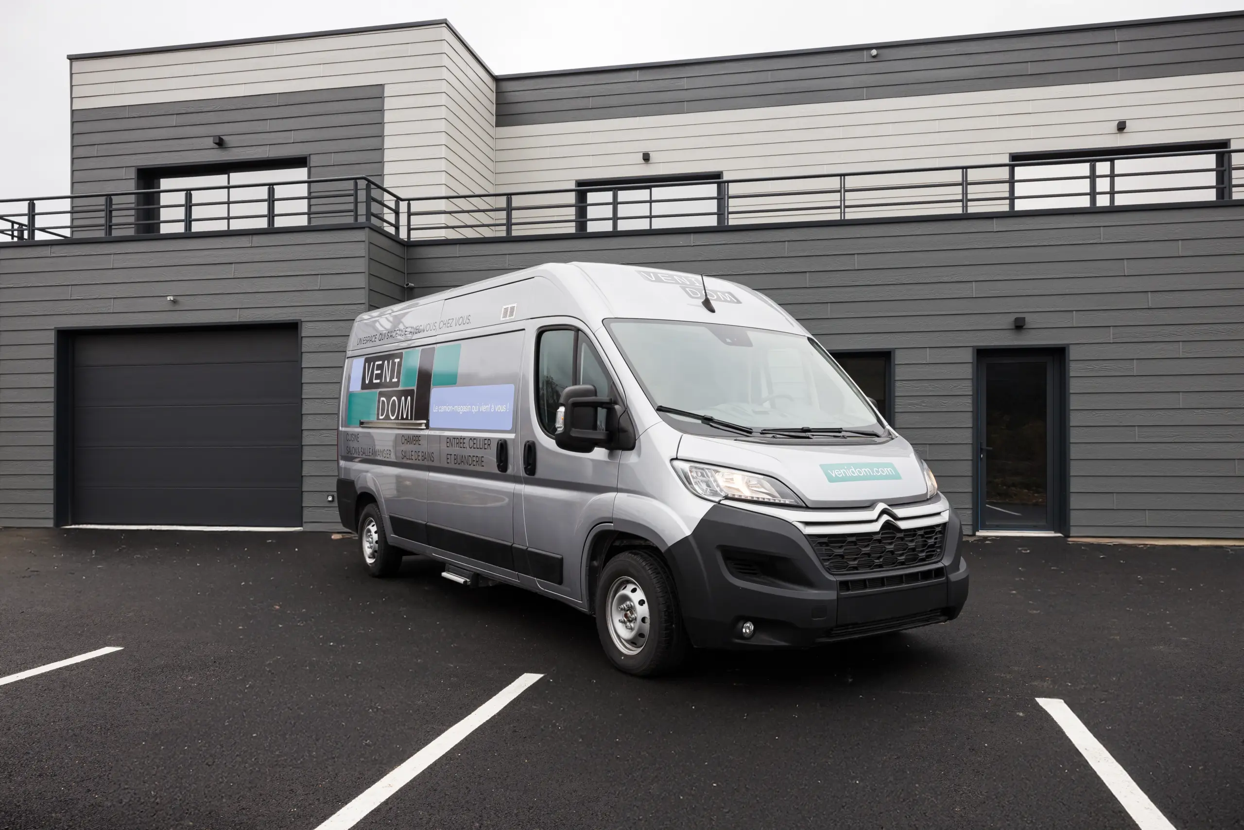 Camion magasin Venidom stationné devant une maison contemporaine, showroom mobile pour projet d’aménagement intérieur sur mesure à domicile