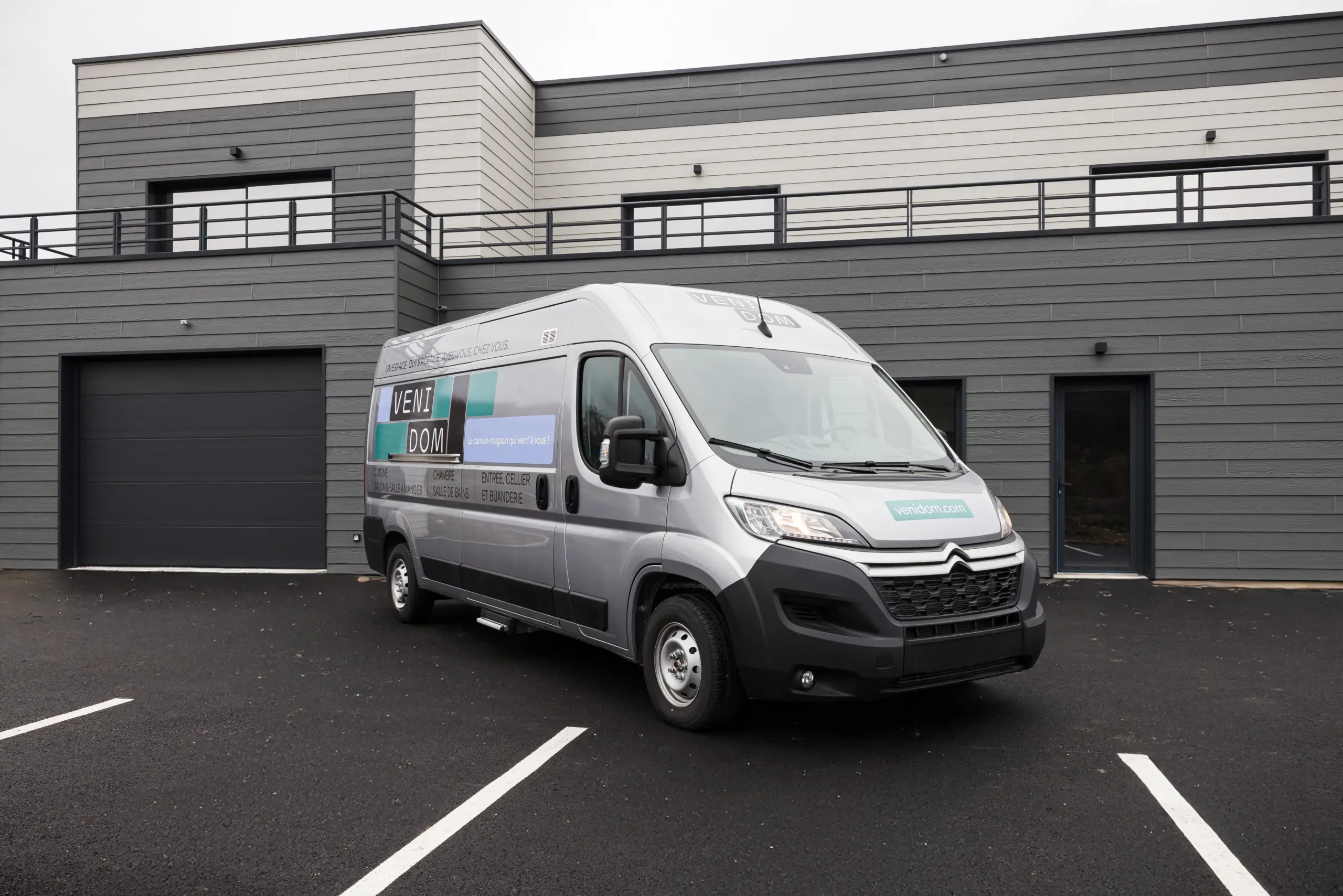 Camion magasin Venidom garé devant une maison contemporaine, showroom mobile d’aménagement intérieur se déplaçant à domicile pour projets sur mesure