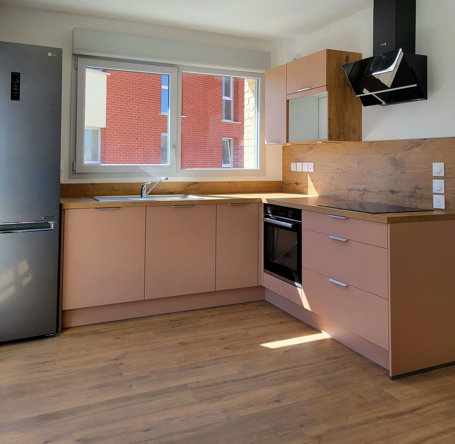 Vue d'ensemble d'une cuisine solaire et chaleureuse optimisant un petit espace avec des finitions épurées et un plan de travail authentique en bois.