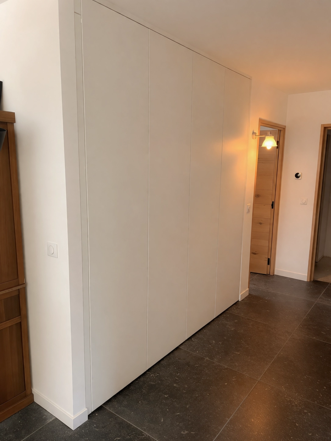 Placard d’entrée sur mesure toute hauteur avec façades blanches épurées et sans poignées, intégré dans un couloir pour optimiser les rangements sans alourdir l’espace