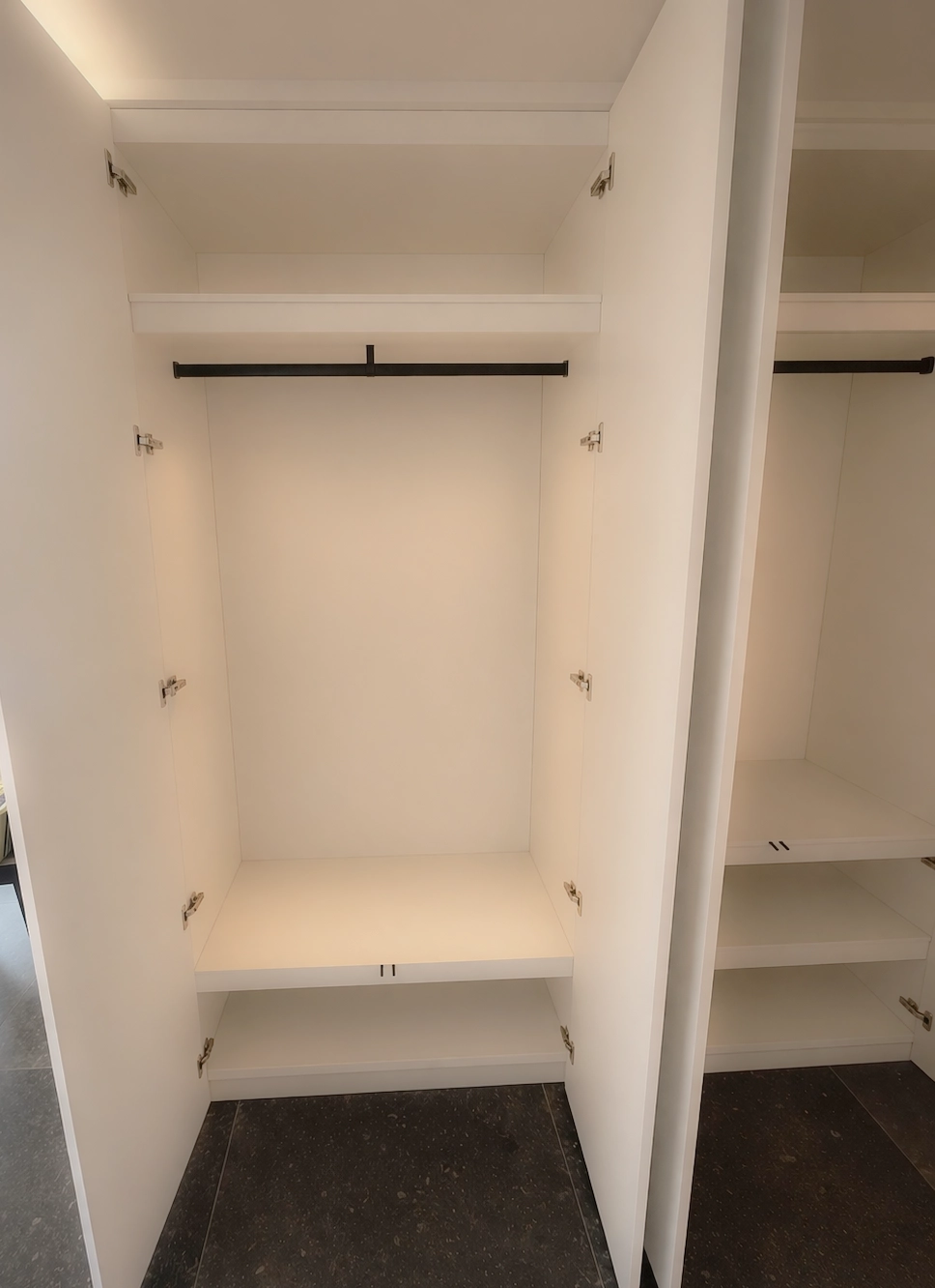 Intérieur de placard sur mesure minimaliste avec penderie et étagères, conçu pour optimiser un couloir et créer des rangements discrets et fonctionnels