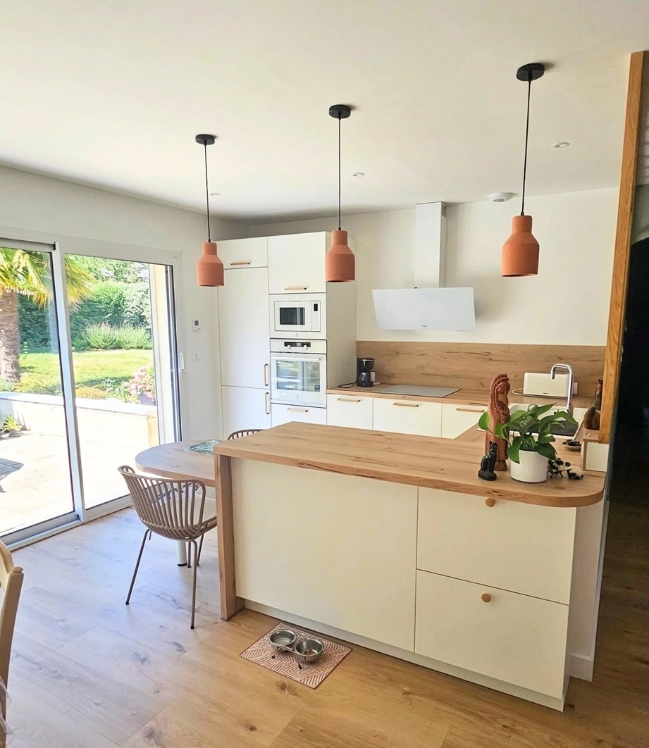 Vue d'ensemble d'une cuisine familiale aménagée en U par Venidom Poitiers, mélangeant des façades blanches lumineuses et un plan de travail en bois chaleureux avec un coin snack intégré.