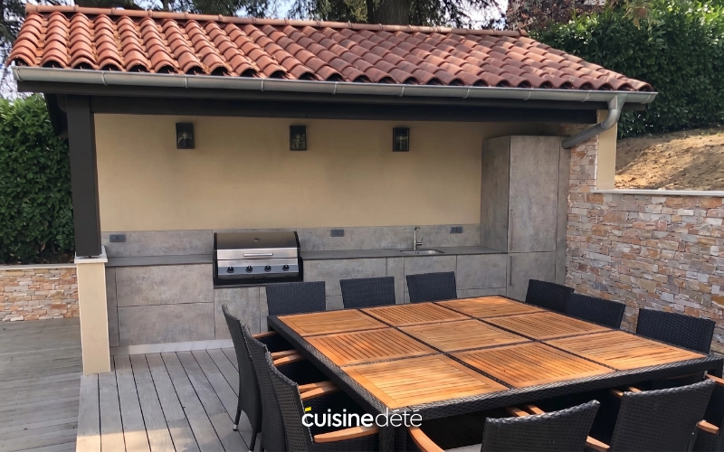 Cuisine d'été installée sous un abri avec espace repas sur terrasse