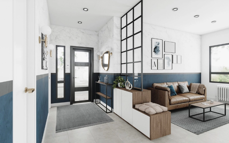 Aménagement d'une entrée lumineuse ouverte sur le salon, séparée par une verrière noire de style industriel posée sur un meuble en bois blanc avec banc intégré. Le hall présente un soubassement bleu canard, un mur effet marbre, une console fine noire et un grand tapis gris.