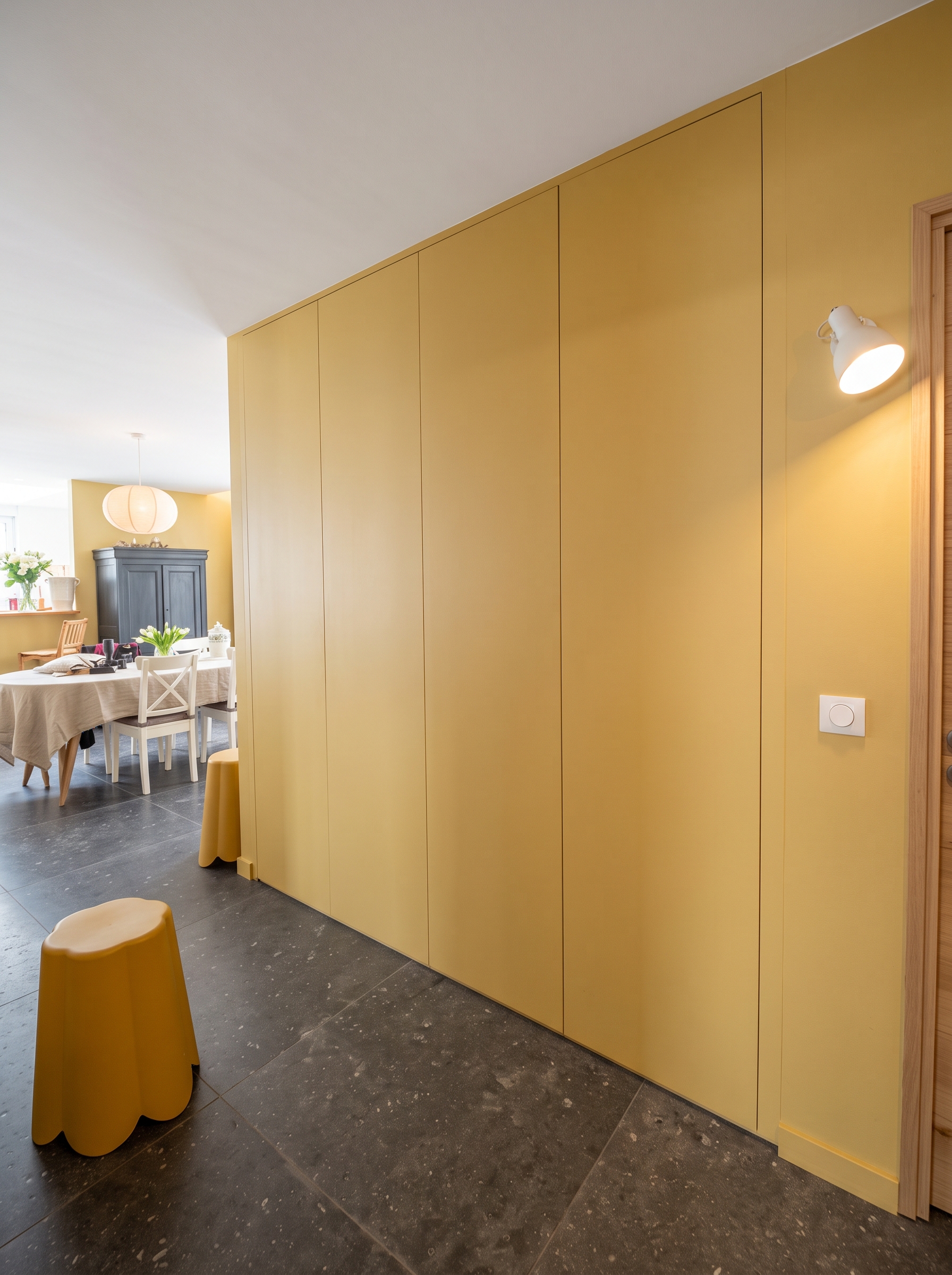 Entrée chaleureuse aux tons jaune miel avec portes sans poignées et rangements optimisés.
